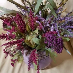 A Fall Floral arrangement in a vase on a couch.