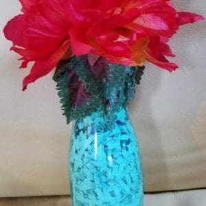 An Inspiration Bottle with red and pink flowers in it.