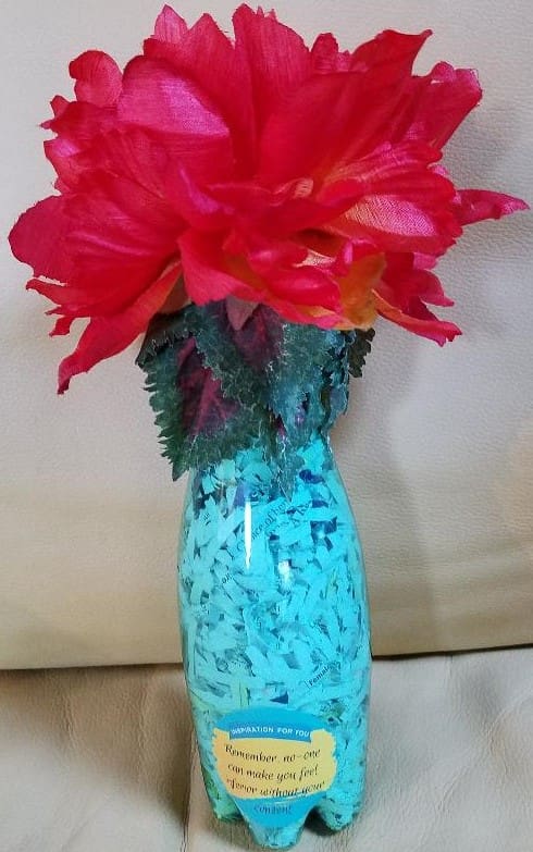 An Inspiration Bottle with red and pink flowers in it.