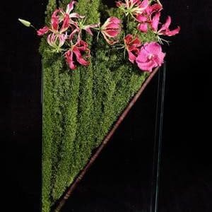 A glass vase with pink flowers and moss in Bamboo Surprise.