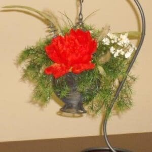 An arrangement of red flowers in a metal vase on a table.