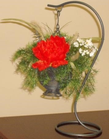 An arrangement of red flowers in a metal vase on a table.