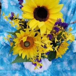 Sunflowers in a vase on a blue cloth.