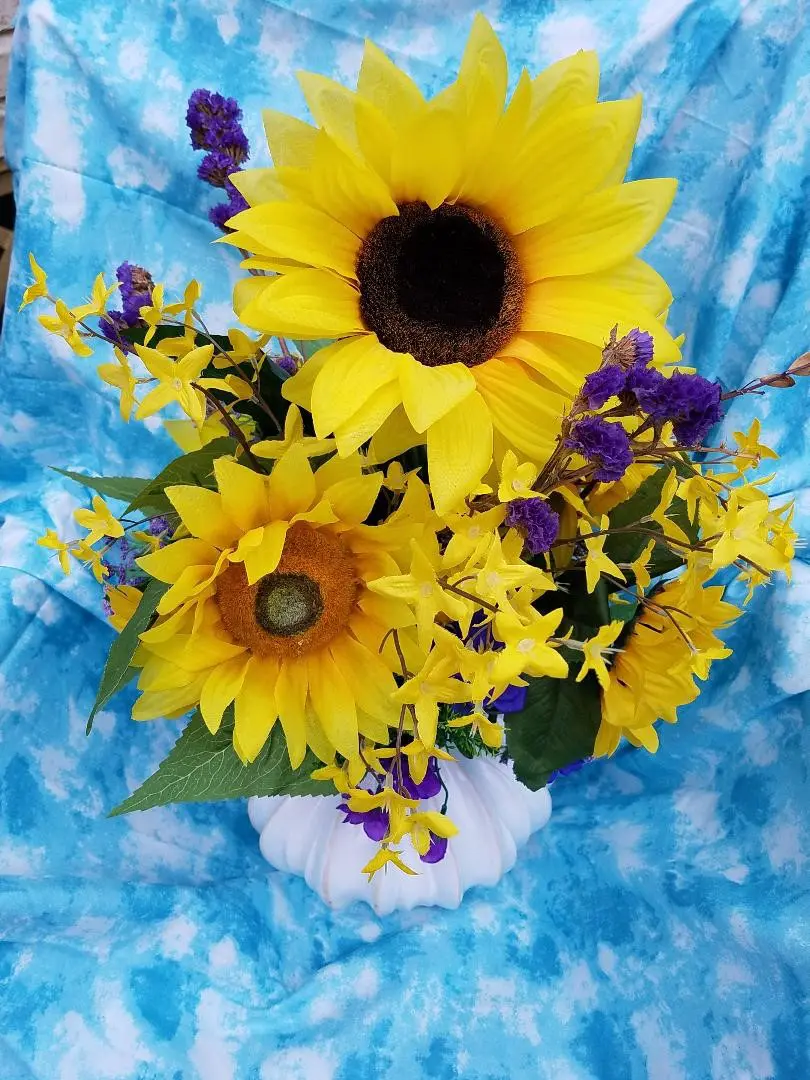 Sunflowers in a vase on a blue cloth.
