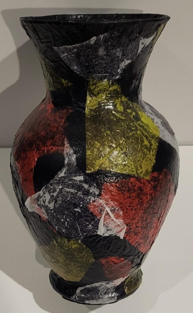 An Art Deco Vase with red, yellow, and black paint on it.