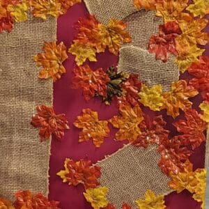 Red fabric with burlap and fall leaves.
