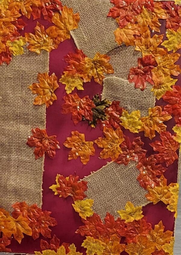 Red fabric with burlap and fall leaves.