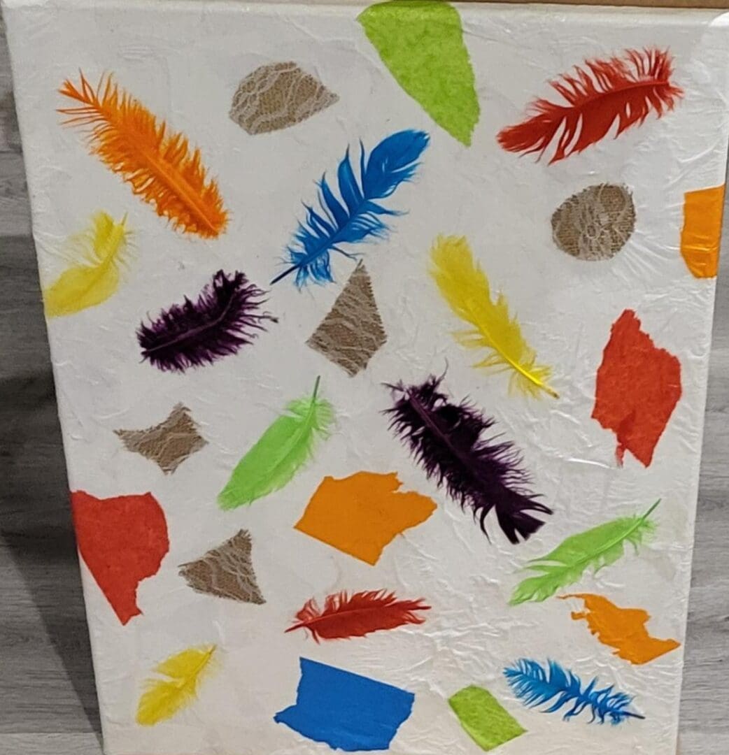 Colorful feathers and paper scraps on canvas.