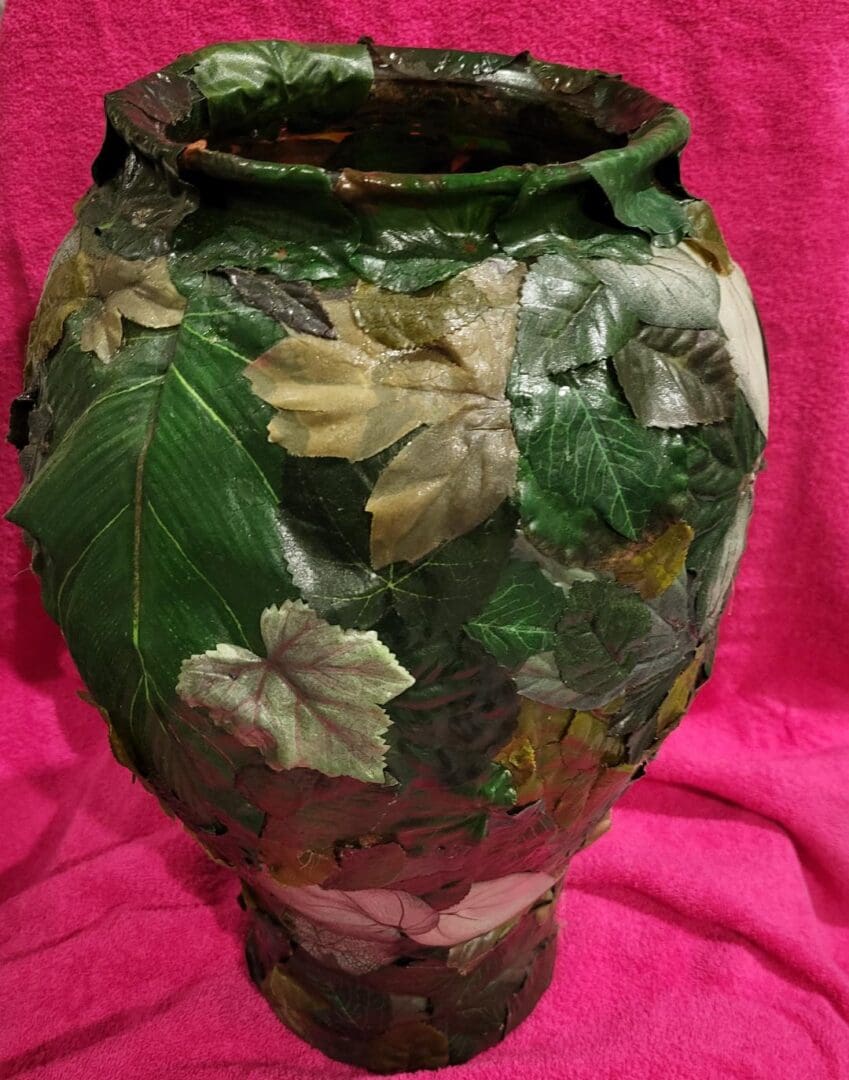 A vase covered in fake leaves.