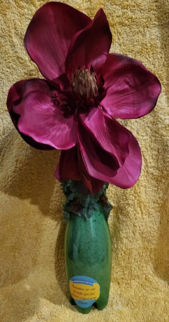 A silk magenta flower in a green bottle.