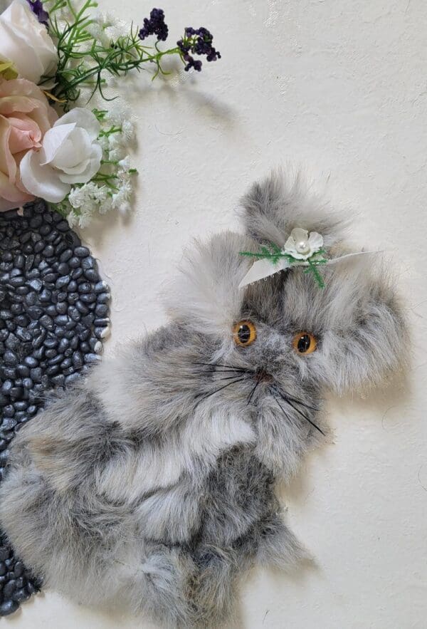 Gray and white kitten with a flower in its hair.