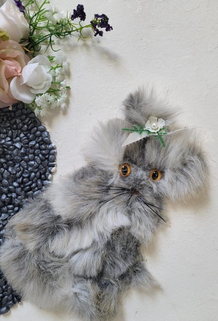 Gray and white kitten with a flower in its hair.