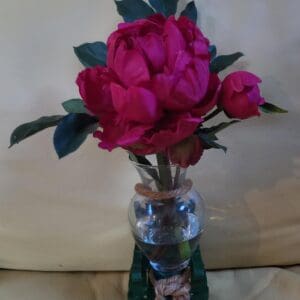 A vase of pink peonies on a table.