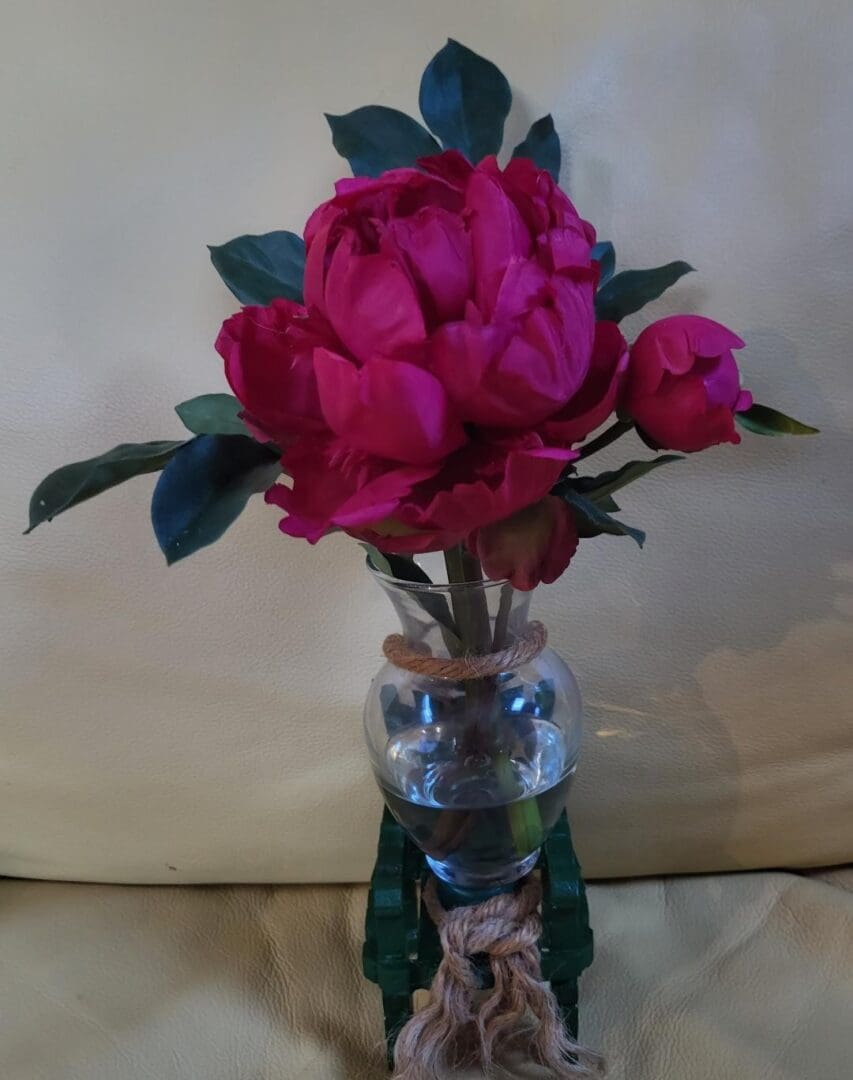 A vase of pink peonies on a table.