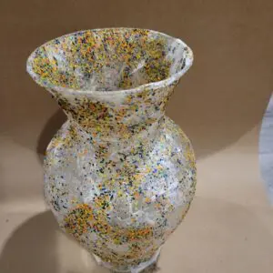 A tall, plastic vase with multi-colored confetti pieces.