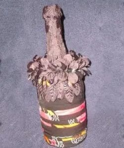 A wine bottle decorated with fabric and flowers.