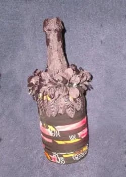 A wine bottle decorated with fabric and flowers.